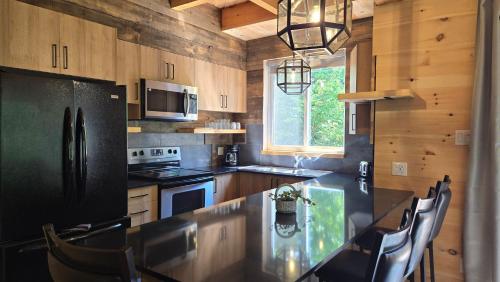a kitchen with a black refrigerator and a table with chairs at L'Appartement du Pavillon - Rafting Momentum in Bryson