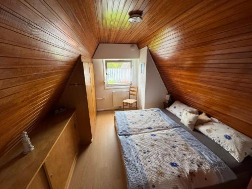 a small room with a bed and a wooden ceiling at Sielhuus in Neuharlingersiel