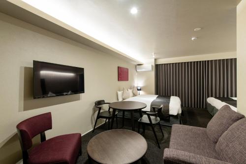 a hotel room with a bed and a table and chairs at Kyohotel Kishotei Goshominami in Kyoto