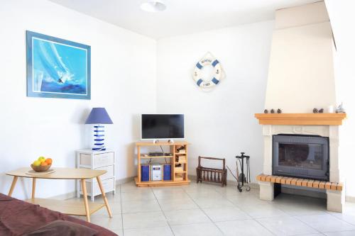 a living room with a fireplace and a tv at Les Tamaris du Nord - Maison à 300m de la plage in Portbail