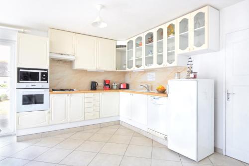 a white kitchen with white cabinets and appliances at Les Tamaris du Nord - Maison à 300m de la plage in Portbail