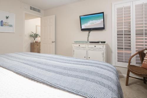 a white bedroom with a bed and a tv on the wall at The Surf Shack in Destin