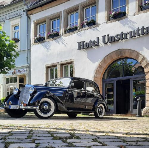 Un coche viejo aparcado delante de una institución hotelera. en Hotel Unstruttal, en Freyburg