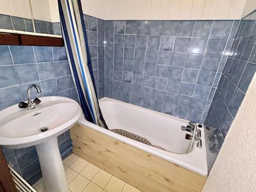 La salle de bains est pourvue de carrelage bleu, d'un lavabo et d'une baignoire. dans l'établissement Appartement cosy 2 pièces, 6 couchages, balcon, garage et casier à skis, Demi-Quartier - FR-1-597-9, à Demi-Quartier