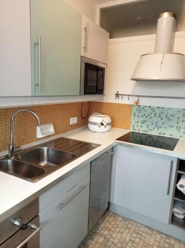 une cuisine avec des armoires blanches et un évier dans l'établissement Appartement 5 personnes, à Saint-Hilaire-de-Riez