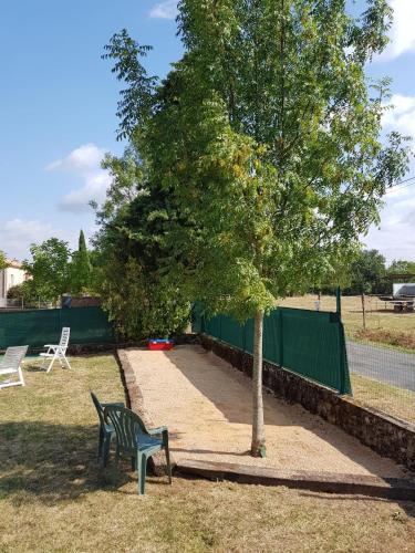 eine grüne Parkbank neben einem Baum in der Unterkunft Chez Alex in Saint-Juéry