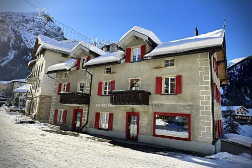 a building with red shutters on a snow covered mountain at Veja Alvra 18 - Cadisch in Bergün