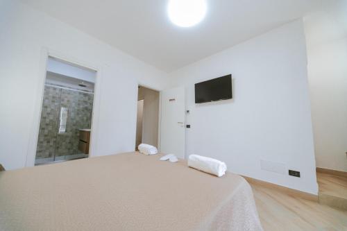a white bedroom with a bed and a tv on the wall at Guest Room 144 in San Giovanni in Fiore