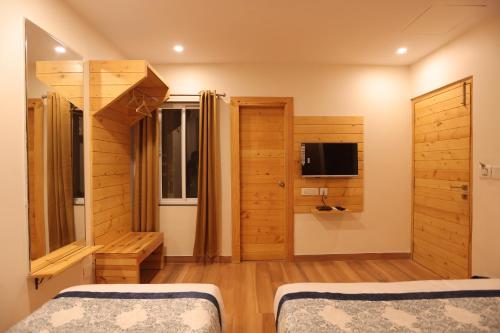 a bedroom with two beds and a tv in it at The Grand Uddhav- A Boutique Hotel in Udaipur
