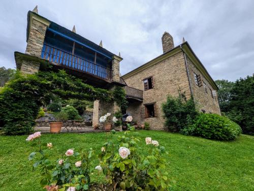 an old stone house with roses in the yard at Casa Doñano in Ribadeo