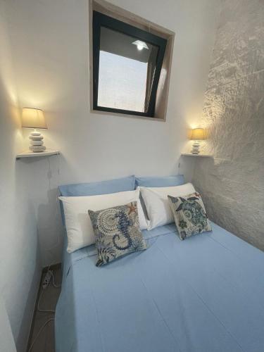a bedroom with a blue bed with pillows and a mirror at BeSanVito - Sea Apartments in Taranto