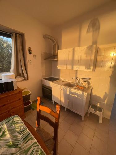 a kitchen with white cabinets and a sink and a chair at BeSanVito - Sea Apartments in Taranto