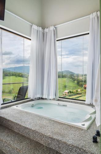 a large bath tub in a room with windows at Vertentes da Mantiqueira - Chalés in Santo Antônio do Pinhal