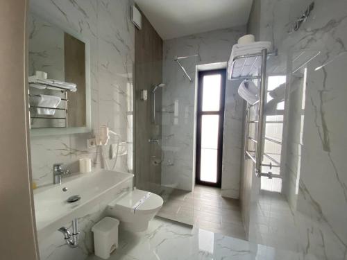 a white bathroom with a toilet and a sink at Mountain Residence Apartments & Chalet in Bukovel