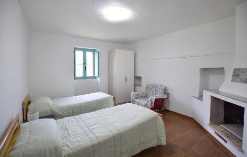 a white room with two beds and a fireplace at 1 Bedroom Cozy Apartment In Longobardi in Longobardi