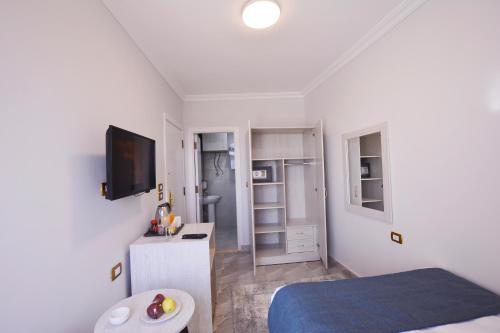 a small white room with a bed and a tv at Topview Pyramids And Museum in Cairo