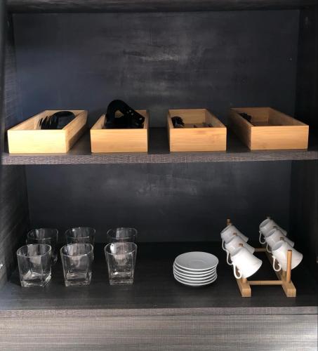 a shelf with plates and glasses and wine bottles at Luxurious Deluxe Apartment - EhubStay Mactan Cebu - Saekyung Condo Looc in Lo-oc