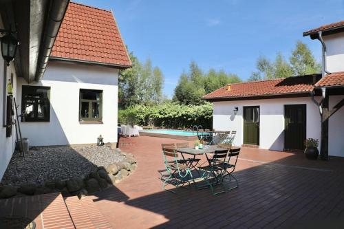 a patio with a table and chairs next to a house at FeWo Gotland Mecklenburg Pool Alte Schule Barlin in Dargun