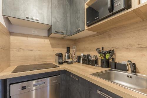 une cuisine avec un évier en acier inoxydable et un comptoir dans l'établissement Les Mélèzes d'Or - Proche des pistes de ski, aux Orres