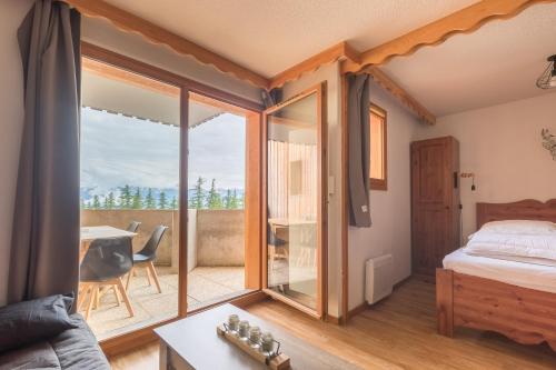 une chambre avec un lit et un balcon avec une table dans l'établissement Les Mélèzes d'Or - Proche des pistes de ski, aux Orres