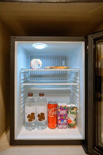 an open refrigerator with drinks and cans of soda at Hotel Clover Asoke - SHA Extra Plus in Bangkok