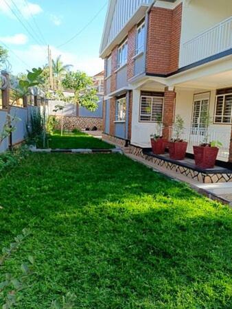 a house with a yard with green grass in front of it at Shiloh homes and travel agency in Kampala