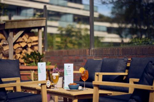 a wooden table with two chairs and drinks on it at WestCord ApartHotel Boschrijck in West-Terschelling