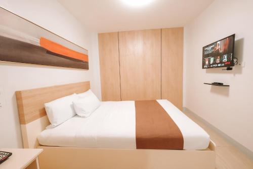 a bedroom with a bed and a tv on the wall at Rosey Hotel in Cabanatuan