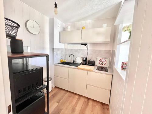 une petite cuisine avec des armoires blanches et une cuisinière dans l'établissement Appartement rénové climatisé avec parking privé près des plages, commerces et restaurants - FR-1-716-68, à La Grande Motte