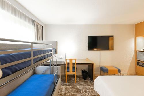 a room with two bunk beds and a desk with a television at Novotel Macon Nord - Porte de Bourgogne in Mâcon
