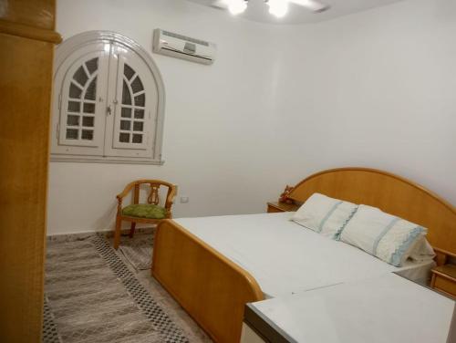 Un dormitorio con una cama y una silla y una ventana. en North Coast Marwa Resort Villa, en Dawwār ‘Abd Allāh