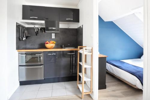 une cuisine avec des armoires noires et un mur bleu dans l'établissement Le Goéland - Second Souffle - Cherbourg, à Cherbourg en Cotentin