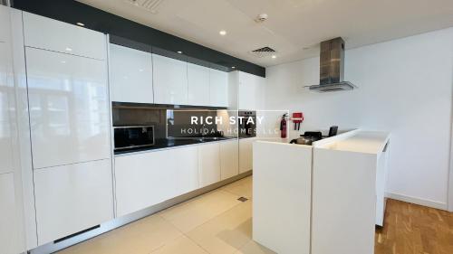 a kitchen with white cabinets and a microwave at Crystal Clear 1BR in Blue Waters with Ain View in Dubai
