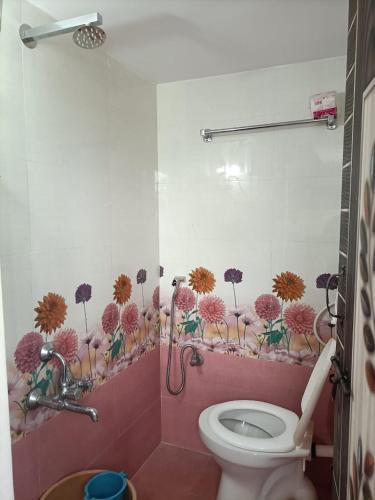 a bathroom with a toilet and flowers on the wall at VIDYA Homestay in Hampi