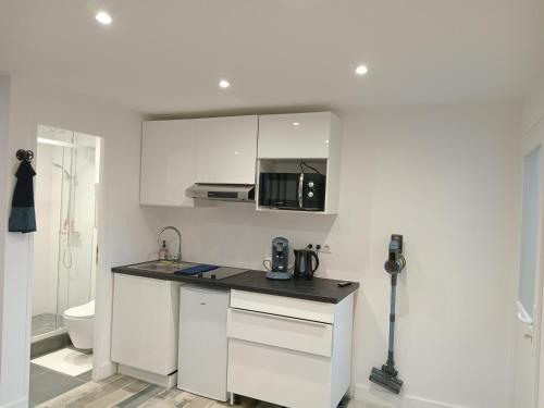- une cuisine blanche avec un comptoir et un four micro-ondes dans l'établissement Studio neuf joliment décoré à 5 min de l'aéroport, à Athis-Mons