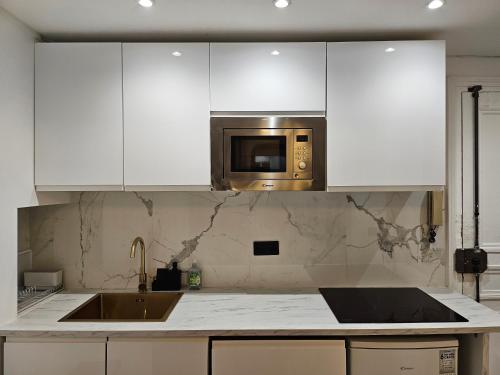 une cuisine avec des armoires blanches et un micro-ondes dans l'établissement Highstay Champs Elysées ARC de triomphe, à Paris