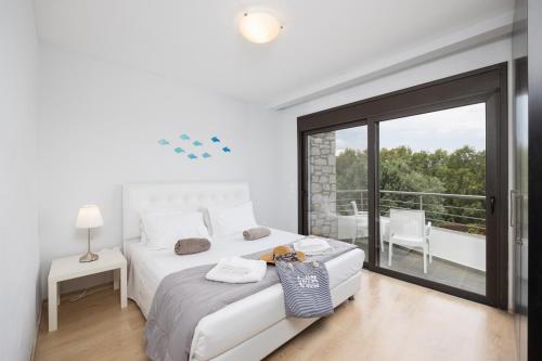 a white bedroom with a large bed and a balcony at Villa Ira in Lachania