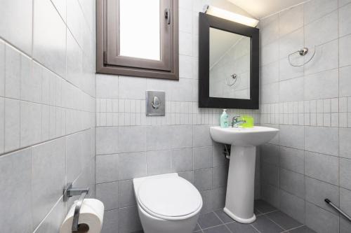 a bathroom with a toilet and a sink and a mirror at Villa Ira in Lachania