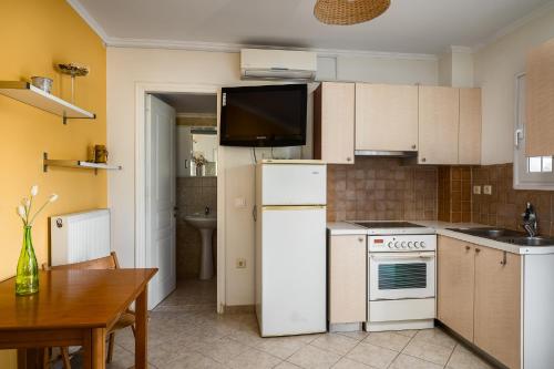 a kitchen with white appliances and a wooden table at Villa Nefeli with Private Pool by Konnect in Dassia