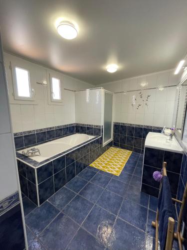 La salle de bains est pourvue de carrelage bleu, d'une baignoire et d'un lavabo. dans l'établissement Appartement Les Saintes, à Saintes-Maries-de-la-Mer
