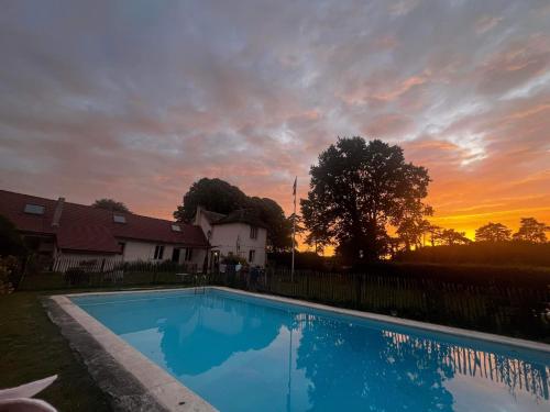 - une piscine en face d'une maison avec un coucher de soleil dans l'établissement La Canardière, à Pendé