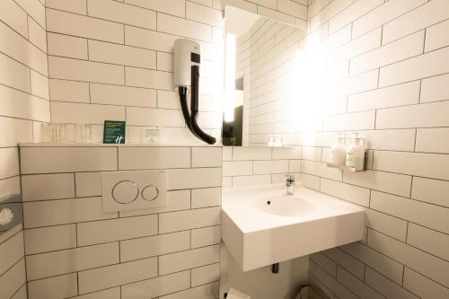 a white bathroom with a sink and a mirror at Holiday Inn Calais-Centre by IHG in Calais