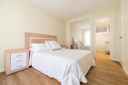 Un dormitorio con una cama blanca y suelo de madera. en Apartamento Cánovas Vigo Center, en Vigo