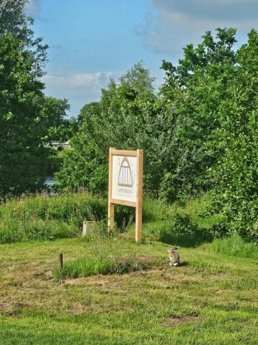 a sign in a field with a cat sitting next to it at Tiny House De Kwekfink in Westergeest