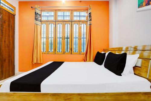 a bedroom with a large bed with an orange wall at SPOT ON The SN Lawn in Lucknow