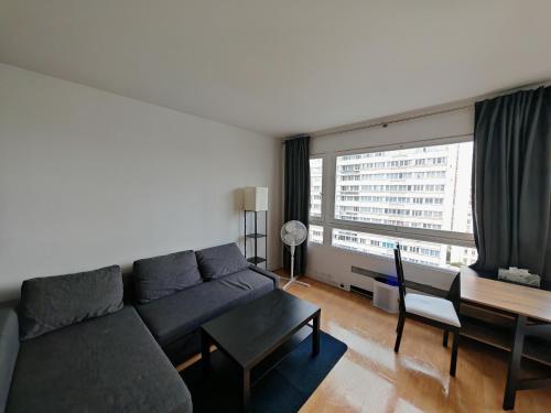 - un salon avec un canapé, une table et une grande fenêtre dans l'établissement Appartement lumineux proche de la ligne 14, à Paris