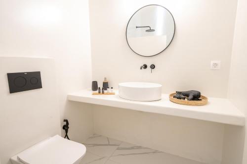 a white bathroom with a sink and a mirror at Alaya Suites in Pirgos