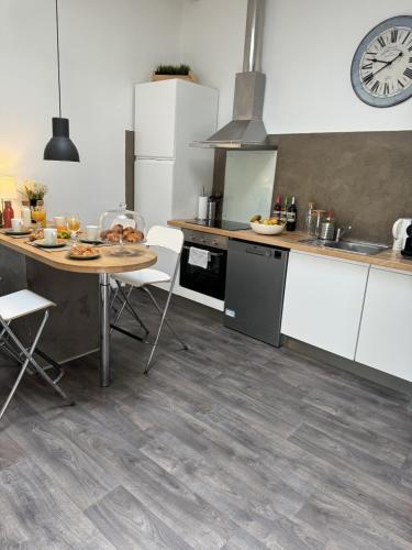 une cuisine avec une table et une horloge au mur dans l'établissement cite 4 Maison Bacou, à Carcassonne