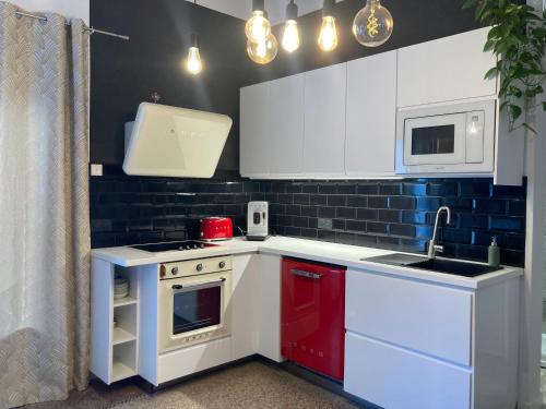 La cuisine est équipée de placards blancs et d'un four avec plaques de cuisson rouges. dans l'établissement Le mazet des 3 piliers, à Nîmes