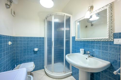 ein blau gefliestes Bad mit einem Waschbecken und einer Dusche in der Unterkunft Capitolo Primo in Porto Venere